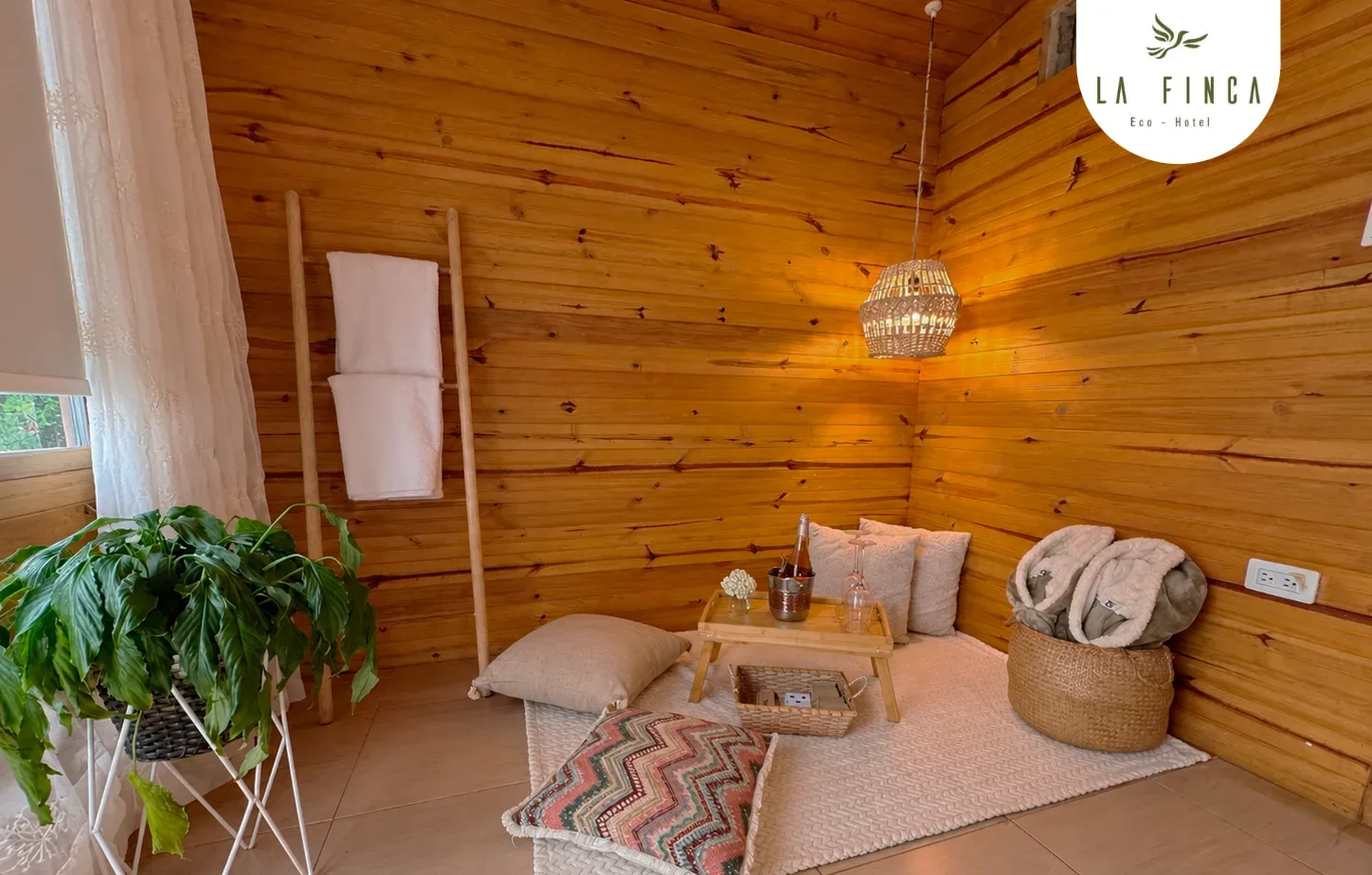 Sala del nivel inferior de la Cabaña 01, con cojines, tapete y plantas