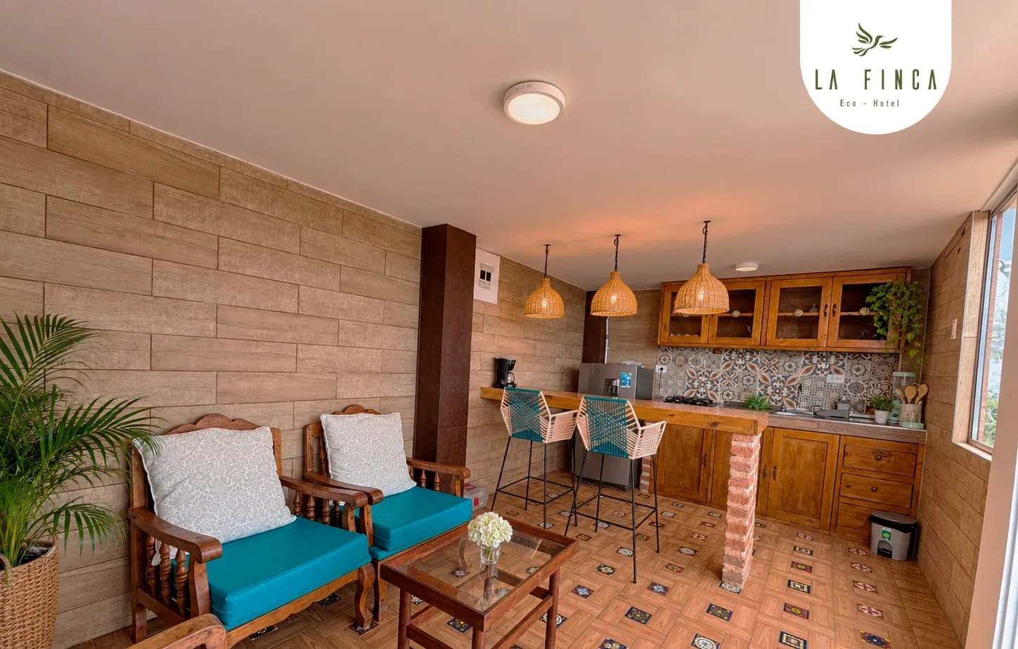 Cocina y comedor del nivel inferior de la Cabaña 01, con barra, sillas altas y sillones