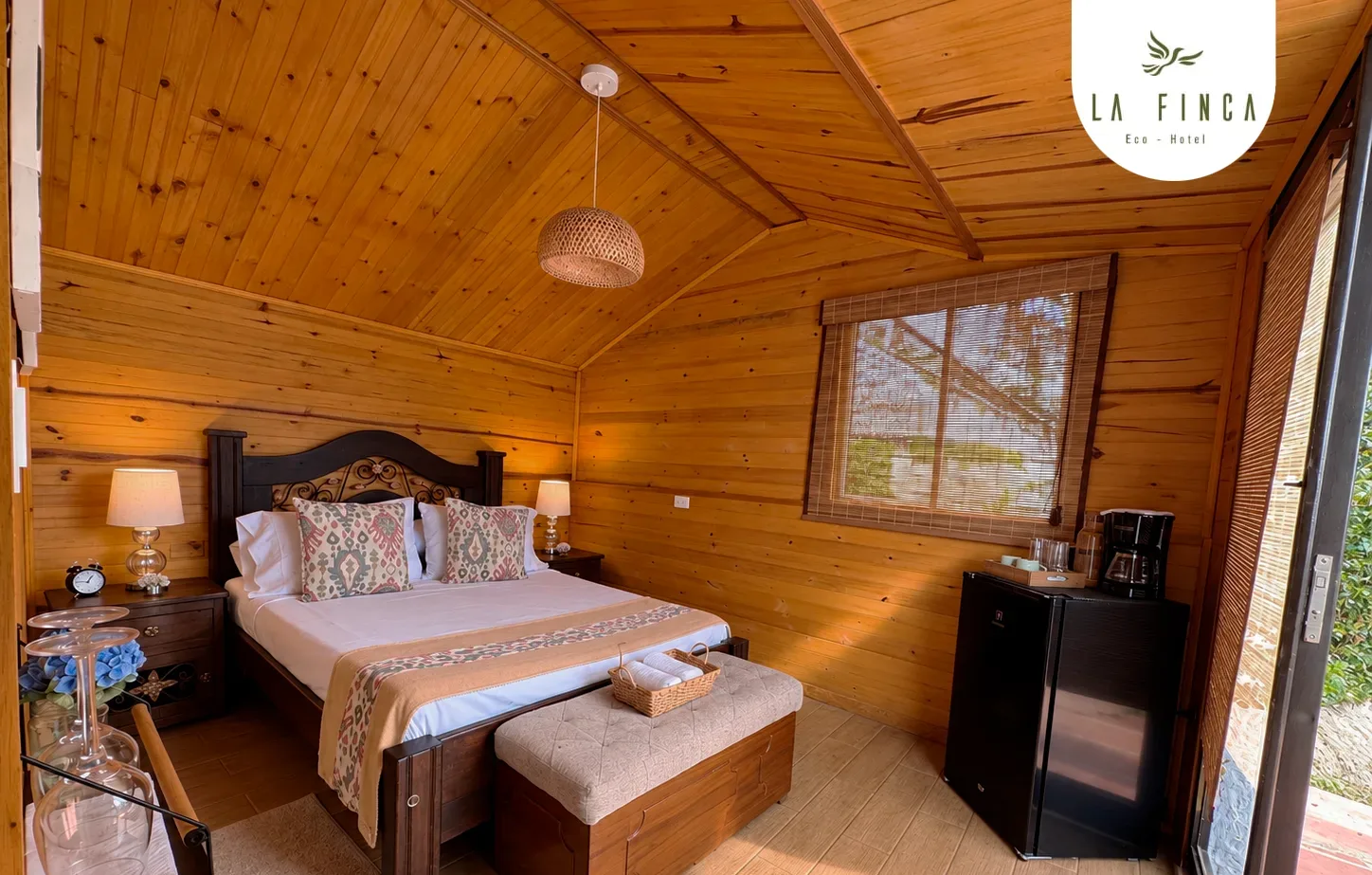 Habitación de la Cabaña 02 con cama doble, paredes de madera y mininevera