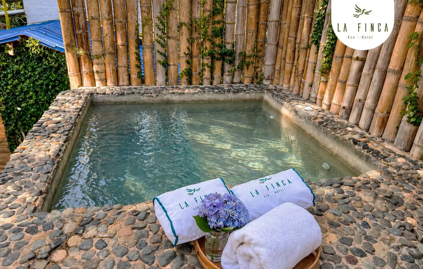 Jacuzzi privado de la Cabaña 02 bajo el árbol, rodeado de guadua, con toallas dobladas