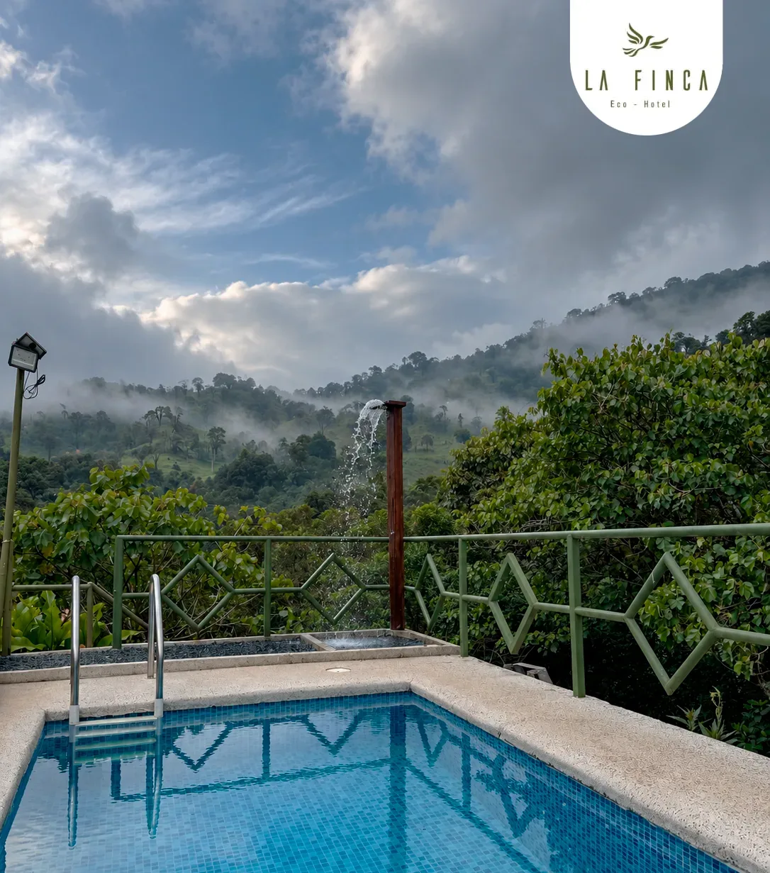 Piscina de agua fría de La Finca con su chorrera, frente a las montañas y las nubes